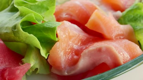 Close up of fresh raw fish slices with greens in a salad