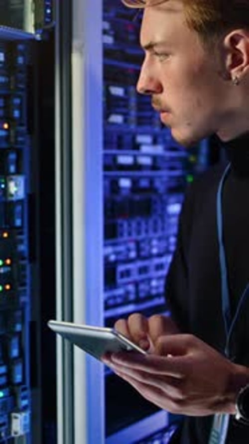 Young Adult Works With Tablet in Server Room