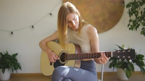 Woman Plays Guitar in Bright Room