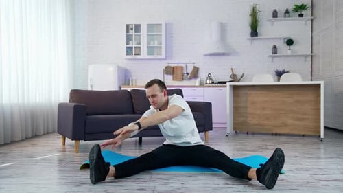 Young Man Stretching at Home on Yoga Mat