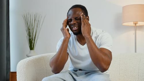 Man Massaging Temples Experiencing Headache Indoors