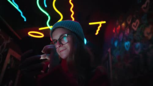 Woman Uses Phone in Neon Lit Interior