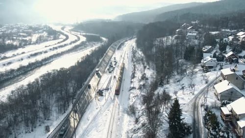 Luftaufnahme des Personenzuges, der am verschneiten Bahnhof ankommt