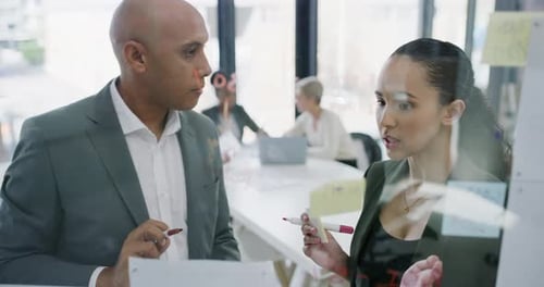 4k video footage of two businesspeople brainstorming with notes a glass wall in an office