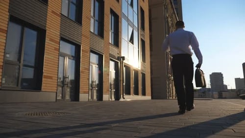 Man Walking With Briefcase Along Sidewalk