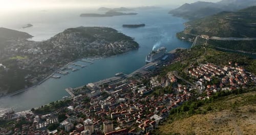 Aerial view of a big cruise ship moored on the harbor of Duvricnik setting sail.