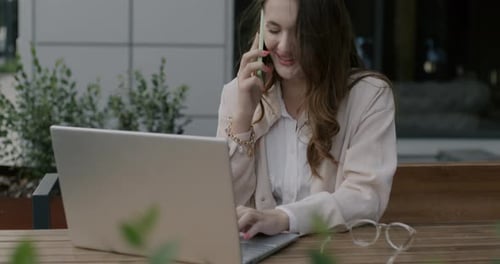 Woman Working at Laptop and Talking on Phone