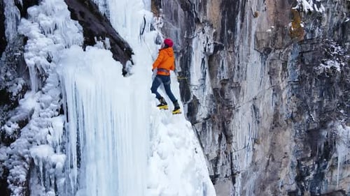 Adult Climber Ascends Frozen Waterfall in Winter