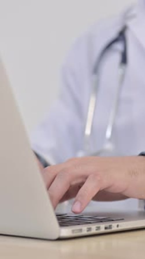 Physician Typing on Laptop in Medical Office