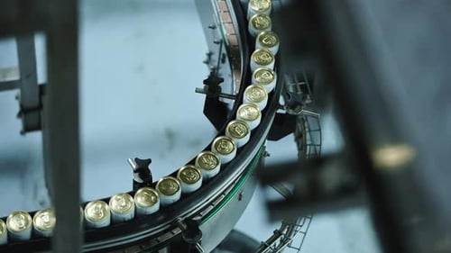 White and gold cans running through a conveyor system in a factory