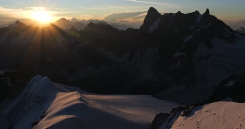 Mountain landscape at sunrise, with snow-covered ridges and jagged peaks