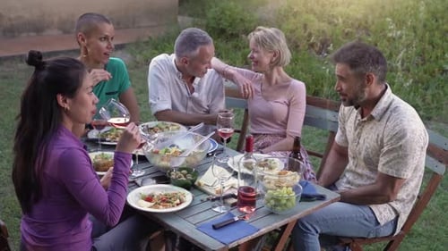 Friends Gather Around Outdoor Dining Table for Meal