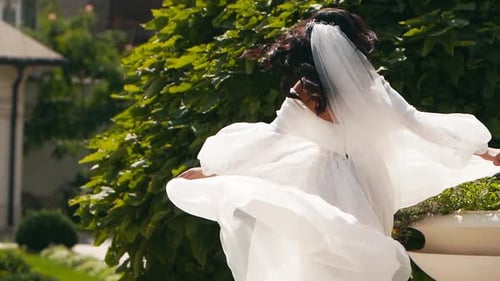 Beautiful Woman in Wedding Dress Walking in Garden