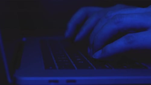 Nahaufnahme von Hackern, die Code auf der Laptoptastatur eingeben.