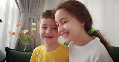 Two Cheerful Children Smiling on a Green Couch