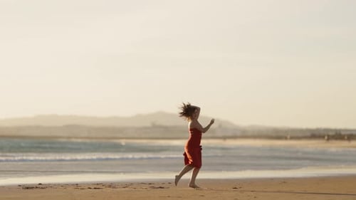 Woman Dancing Barefoot on Beach at Sunset