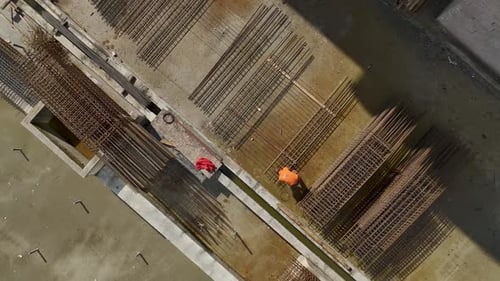 Vídeo aéreo de trabajadores con barras de refuerzo en la plataforma del edificio