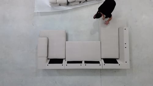 Adult Assembling Modular Sofa from Aerial Perspective