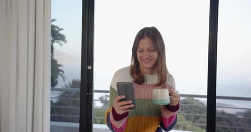 Young Woman Using Phone and Drinking Coffee Indoors