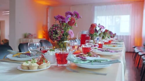 Table familiale festive avec fleurs, plats faits maison et boissons à base de compote rouge en Lettonie