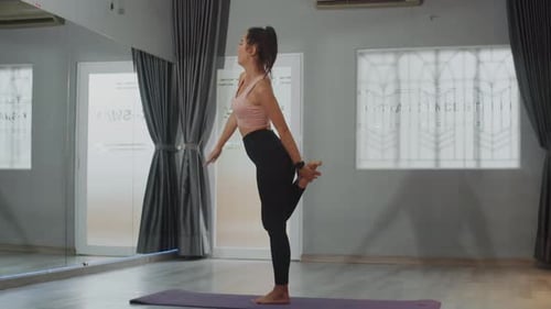 Sportswoman Balancing on One Leg while Stretching in Studio
