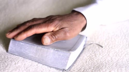 Mann betet zu Gott mit Händen zusammen mit Bibel Karibischer Mann betet mit weißem Hintergrund Stock