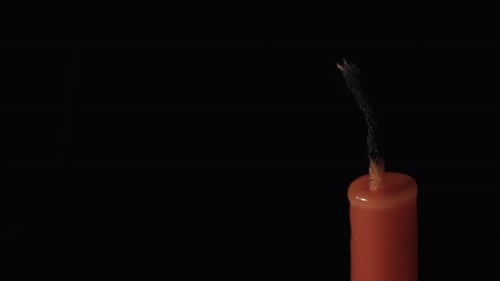 Red candle on a black background, in motion, slider shot, extinguish a candle, smoke from a candle,