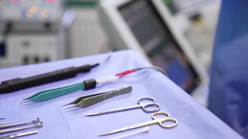Surgical scissors, forceps and electric medical devices on the table in surgery room. Close up