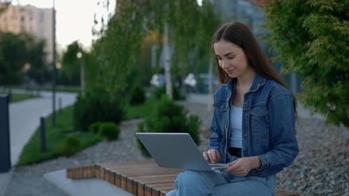 Caucasian Woman Sitting on the Bench Working on the Laptop Near the Business Centre