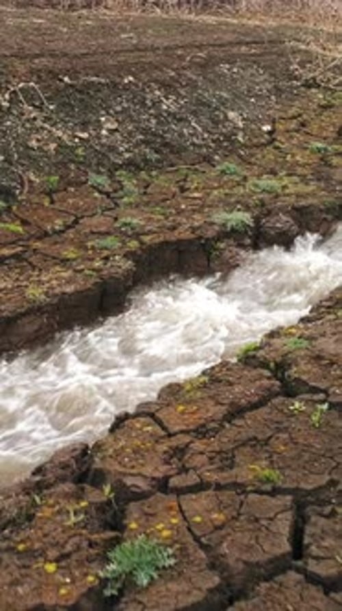 Luftaufnahme eines tief rissigen Bodens und eines kleinen Bachlaufs, Konzept der Trockenklimaökologie und