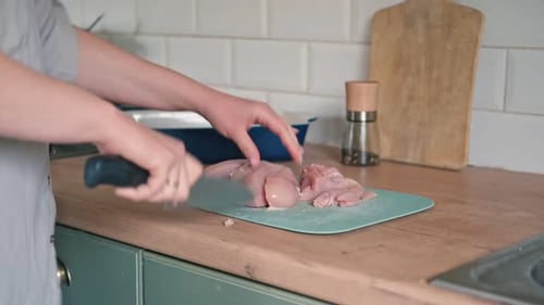 Açougueira corta carne crua com faca afiada na cozinha de casa Mulher cortando o filé de frango