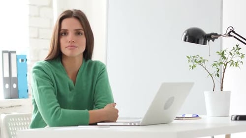 Woman Sitting at Desk Looking at Camera