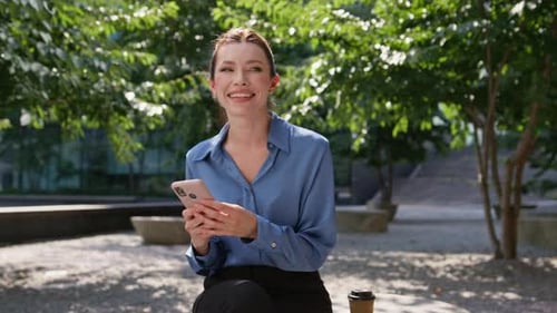 Joyful Girl Browsing Social Media at Mobile Phone Sitting Sunny Street Closeup