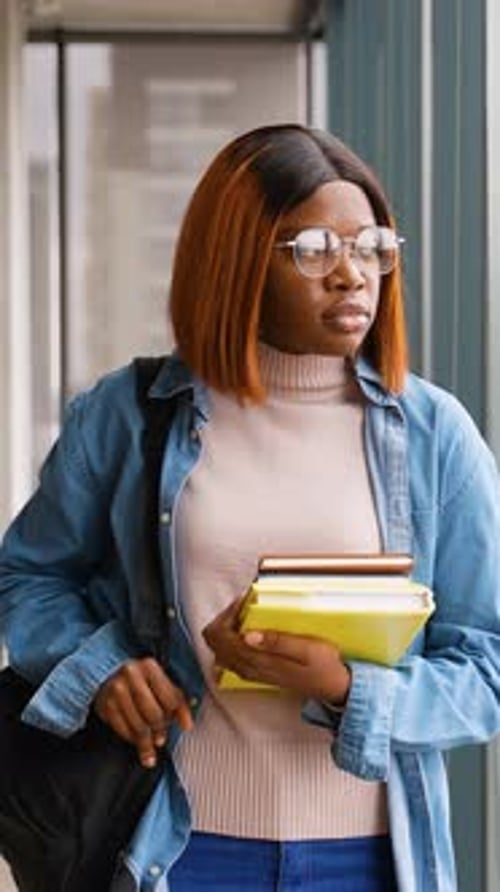 African American Student Leaving Library with Books and Backpack
