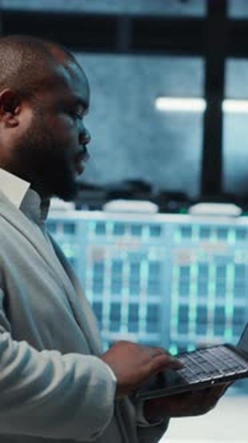 Man Works On Laptop in Data Center