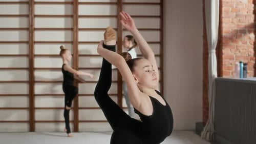 Schoolgirl in Tracksuit Practicing Difficult Gymnastic Exercise in Gym