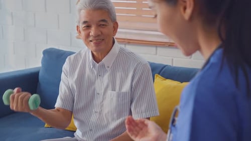 Senior Man Exercises with Dumbbell at Home with Caregiver