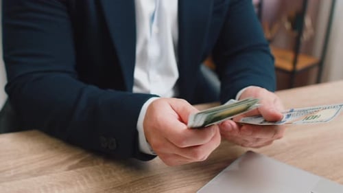 Hands Counting American Dollars at Wood Desk