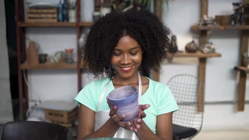 African woman make earth ware at workshop.