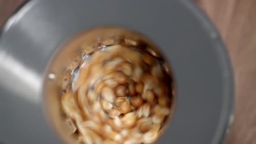 Top view: Golden popcorn kernels spin in hot air popper, waiting to pop.
