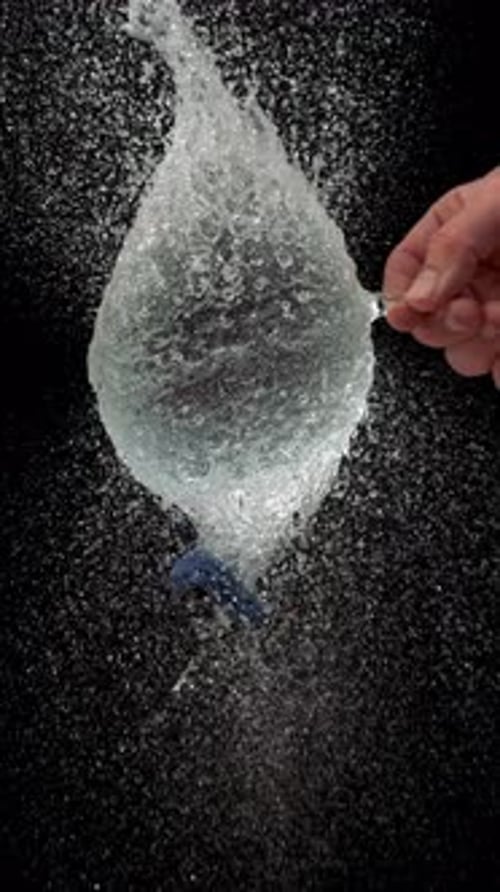 Globo de agua azul en cámara lenta que estalla por la punción de una aguja