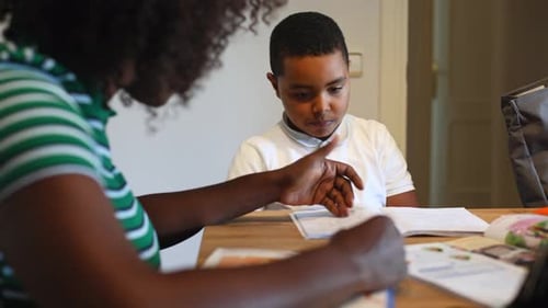 Child Doing Homework With Adult Helper at Table