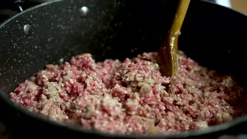 Stirring minced meat with onions in a pan with wooden spoon. slow motion