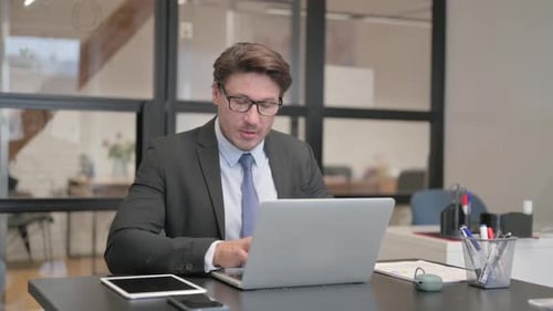 Thumbs Up by Middle Aged Businessman on Laptop in Office