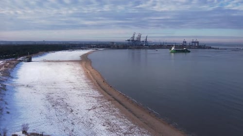 Luftaufnahme der Kräne der Hafenkanal-Werft im Hafengebiet: Schneebedeckter Strand, Meereswellen eingefangen