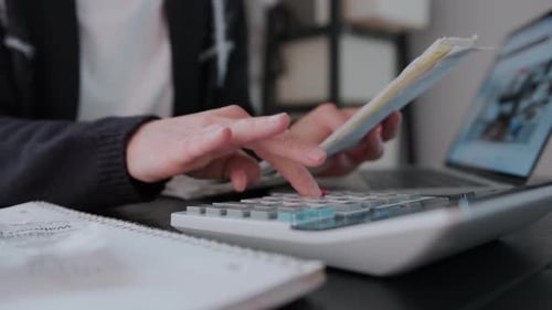 Woman Checking Bills Taxes Bank Account Balance and Calculating Expenses in the Living Room at Home