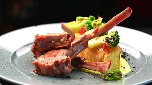 Lamb chops served with vegetables at a restaurant during dinner time.