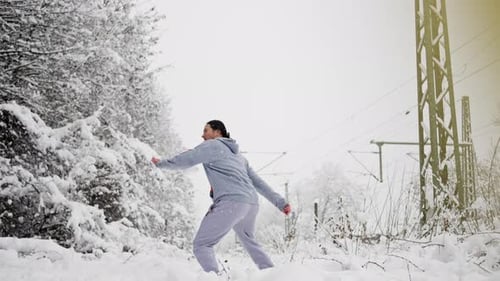 Woman Practicing Martial Arts Kicks in Winter Snow