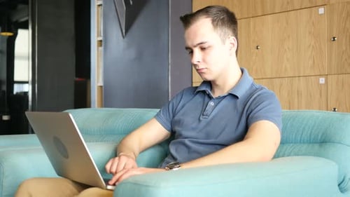 Young Adult Typing on Laptop in Modern Office