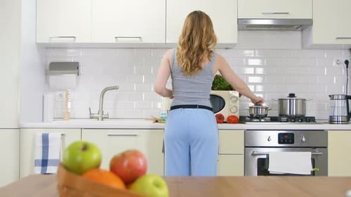 Backside View Long Haired Slim Woman Cooks Dinner in Nice Kitchen